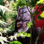 Large Easter Island-like statue of a face partially hidden by trees