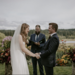Smiling bride and groom looking at each other in front of an officiant