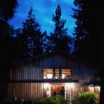 The Barn, doors open and lights on, under a night sky