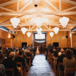 Rows of chairs and audience watching a bride and groom standing in front of an officiant in front of closed doors